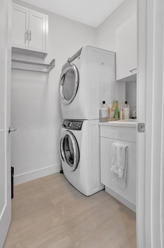 laundry room featuring cabinets and stacked washing maching and dryer