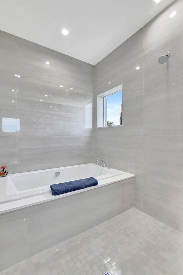 bathroom with tile patterned flooring, tile walls, and tiled bath