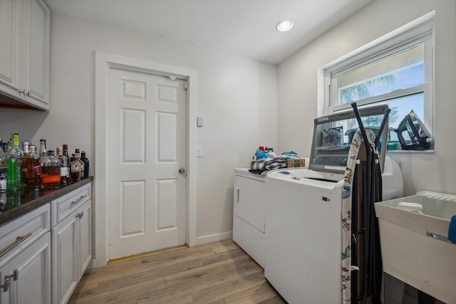 washroom with cabinets, separate washer and dryer, sink, and light hardwood / wood-style flooring