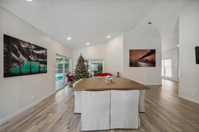 kitchen with vaulted ceiling, a textured ceiling, and light wood-type flooring