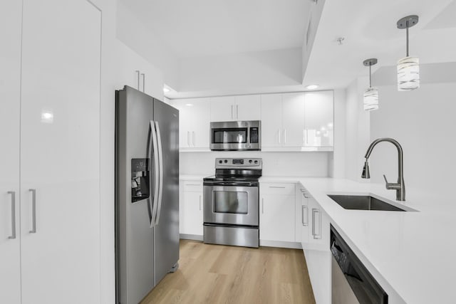 kitchen with hanging light fixtures, white cabinetry, stainless steel appliances, and light countertops