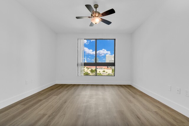 empty room featuring light wood-type flooring, baseboards, and a ceiling fan