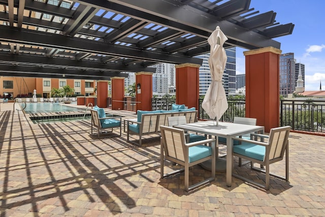 view of patio / terrace featuring a city view, a pergola, and outdoor dining space