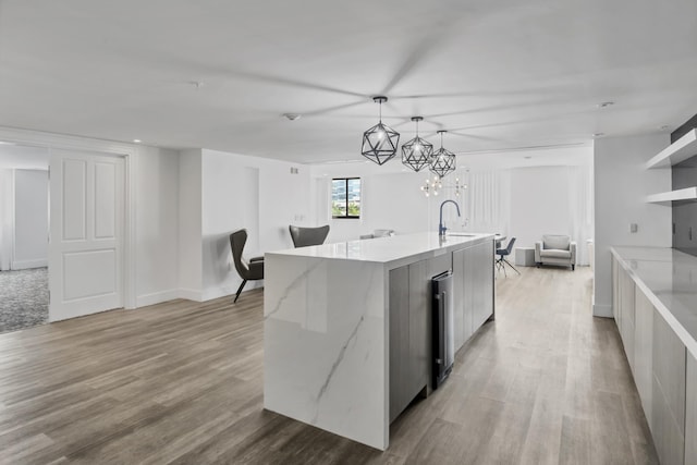 kitchen featuring open floor plan, light wood-type flooring, a large island with sink, and pendant lighting