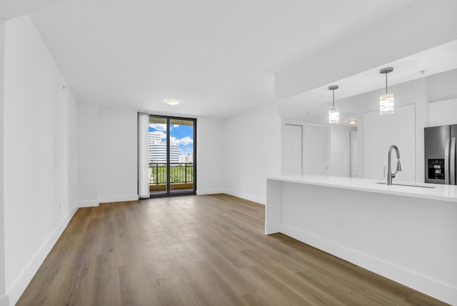 unfurnished living room with floor to ceiling windows, wood finished floors, a sink, and baseboards