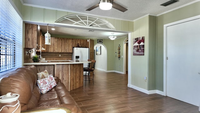 kitchen with dark hardwood / wood-style floors, decorative light fixtures, white refrigerator with ice dispenser, kitchen peninsula, and a textured ceiling