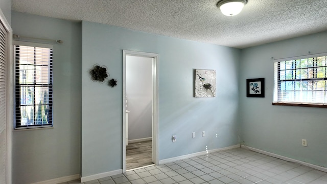 spare room with light tile patterned flooring and a textured ceiling