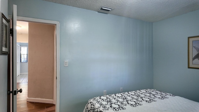 bedroom with light hardwood / wood-style flooring and a textured ceiling