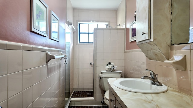 bathroom with vanity, a tile shower, tile walls, and toilet