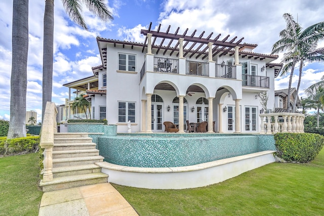 back of house featuring a yard, french doors, a balcony, and stucco siding