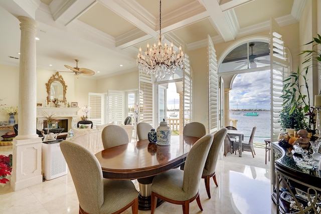 dining area with ceiling fan with notable chandelier, decorative columns, a healthy amount of sunlight, and a water view