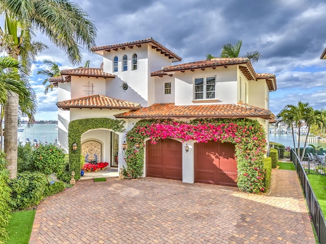 mediterranean / spanish-style house with a garage and a water view