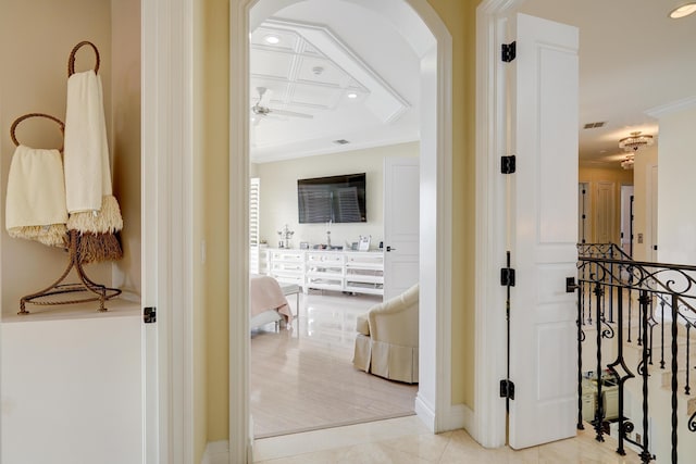 hallway with coffered ceiling, light tile patterned floors, and ornamental molding