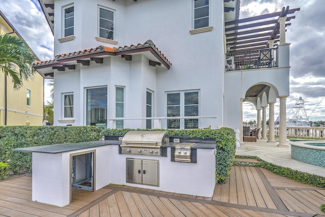 wooden deck with area for grilling, a patio area, and exterior bar