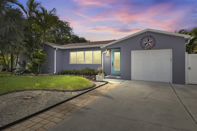 single story home featuring a garage and a yard