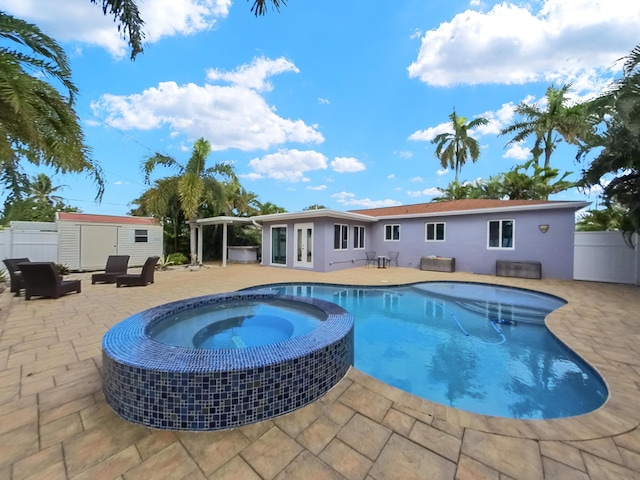 view of swimming pool featuring an in ground hot tub, a storage unit, and a patio area