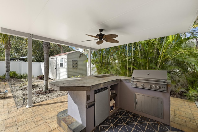 view of patio / terrace featuring area for grilling, a grill, ceiling fan, and a storage unit