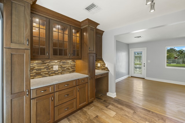 bar with tasteful backsplash, light stone countertops, and light wood-type flooring