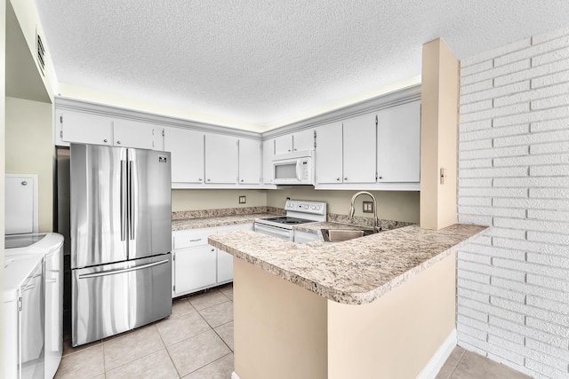 kitchen with washing machine and clothes dryer, sink, light tile patterned floors, kitchen peninsula, and white appliances