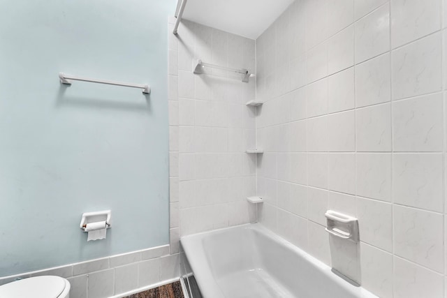 bathroom featuring tiled shower / bath combo and toilet