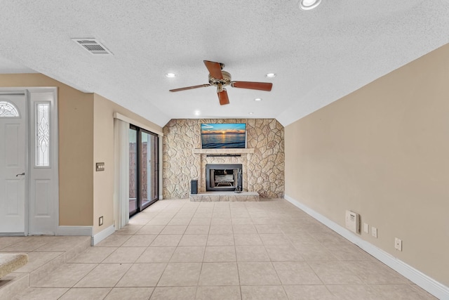 unfurnished living room featuring a stone fireplace, vaulted ceiling, a textured ceiling, light tile patterned floors, and ceiling fan