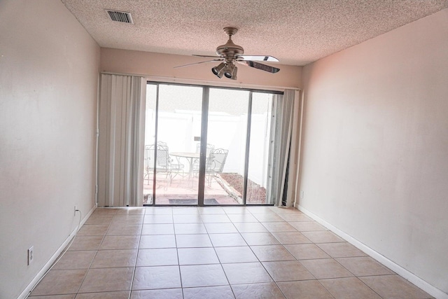 empty room featuring light tile patterned floors, a textured ceiling, and ceiling fan