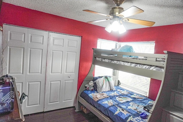 bedroom featuring dark wood-type flooring, a textured ceiling, ceiling fan, and a closet