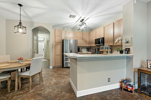 kitchen with pendant lighting, stainless steel refrigerator, kitchen peninsula, and light brown cabinets