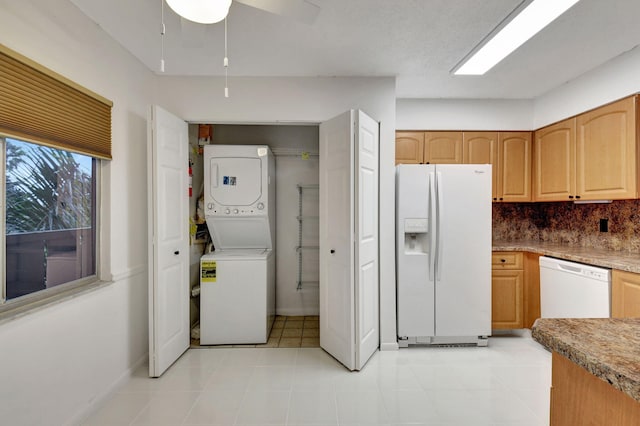 kitchen with tasteful backsplash, stacked washing maching and dryer, light tile patterned floors, and white appliances