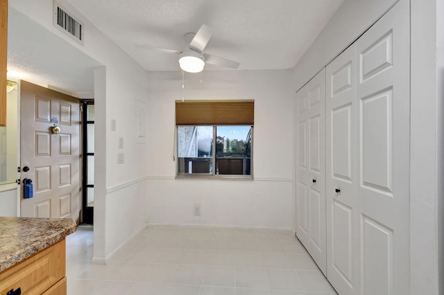 interior space with light tile patterned floors, a textured ceiling, and ceiling fan