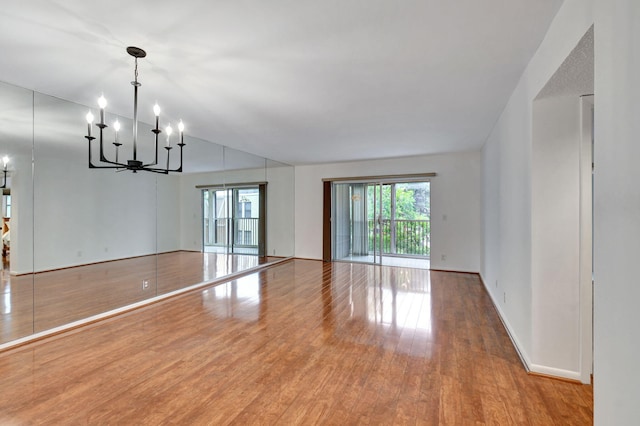 empty room featuring a notable chandelier and light hardwood / wood-style flooring