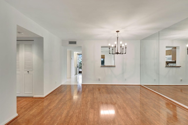 spare room with an inviting chandelier and light hardwood / wood-style flooring