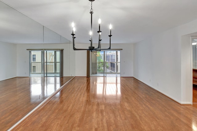 unfurnished dining area featuring ceiling fan with notable chandelier and hardwood / wood-style floors