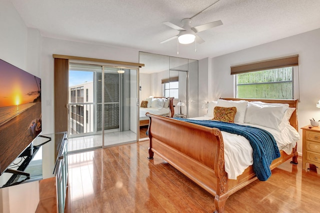 bedroom with ceiling fan, wood-type flooring, a textured ceiling, and access to outside