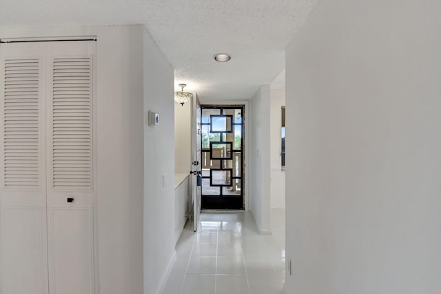 hallway featuring light tile patterned flooring, a wall of windows, and a textured ceiling