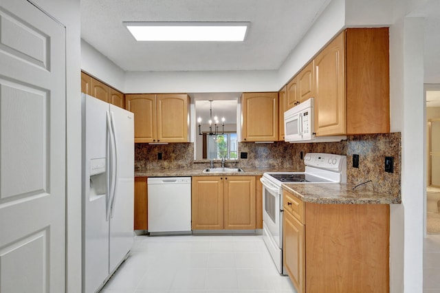 kitchen featuring sink, tasteful backsplash, light stone counters, a chandelier, and white appliances