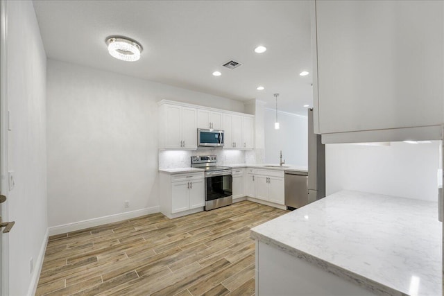 kitchen featuring sink, white cabinetry, appliances with stainless steel finishes, kitchen peninsula, and backsplash