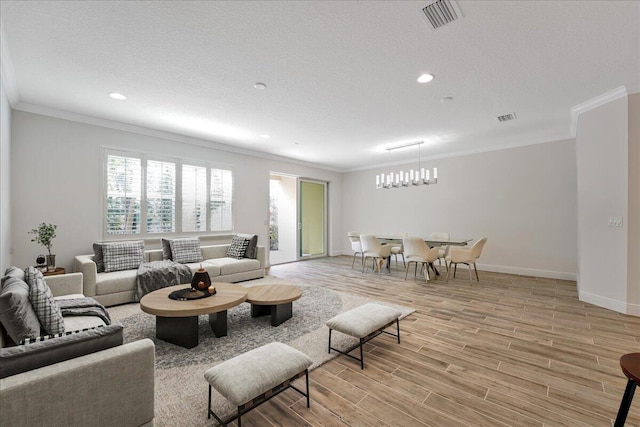 living room with ornamental molding, a textured ceiling, and light wood-type flooring