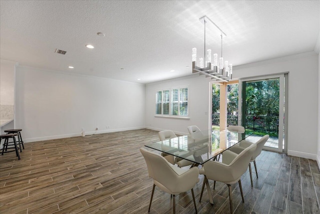 dining area with dark wood-type flooring, crown molding, an inviting chandelier, and a textured ceiling