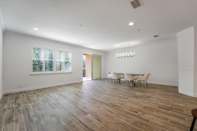 unfurnished room featuring wood-type flooring, ornamental molding, and a textured ceiling