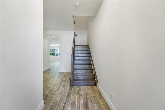 stairs with hardwood / wood-style floors and a textured ceiling