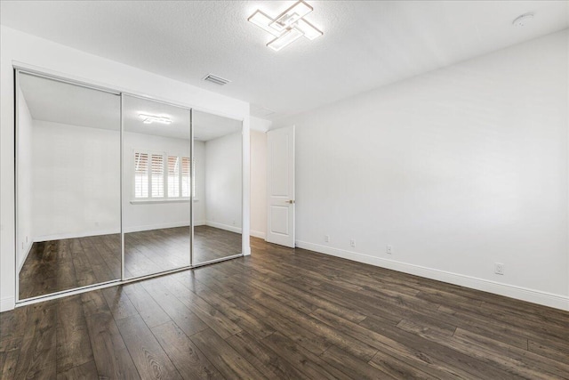 unfurnished bedroom with dark wood-type flooring, a closet, and a textured ceiling