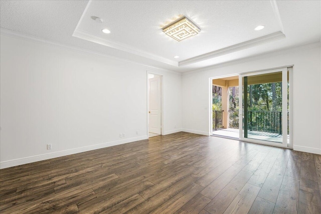 empty room with dark wood-type flooring, a tray ceiling, and crown molding