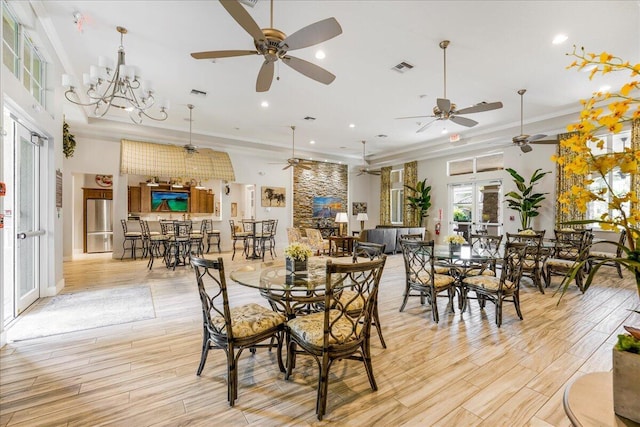 dining space with crown molding, a towering ceiling, light hardwood / wood-style flooring, and a notable chandelier