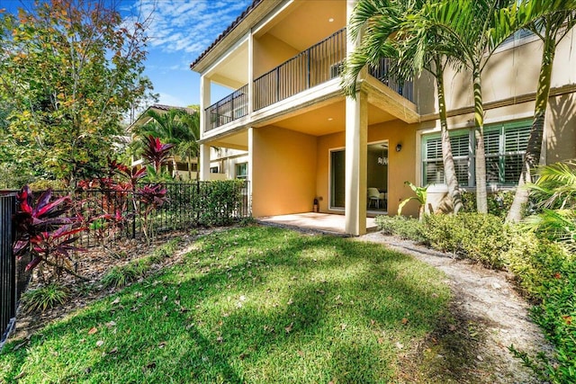 rear view of house featuring a patio area, a balcony, and a lawn