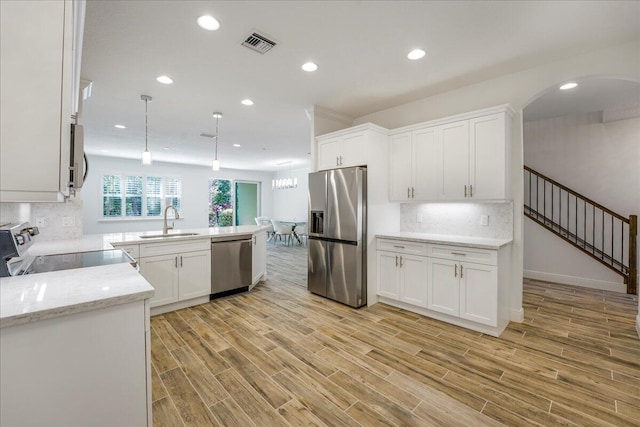 kitchen with white cabinetry, sink, decorative light fixtures, and stainless steel appliances