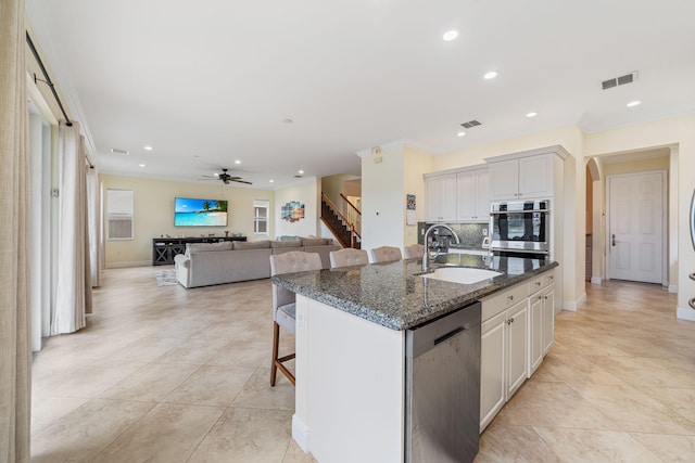 kitchen featuring a kitchen island with sink, sink, white cabinets, and appliances with stainless steel finishes