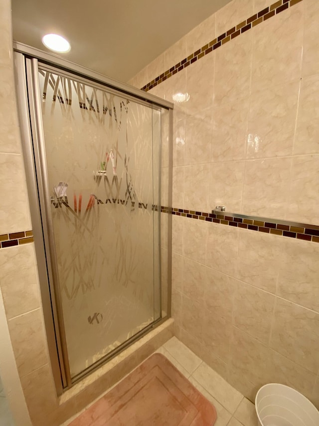 bathroom featuring walk in shower, tile patterned flooring, and tile walls