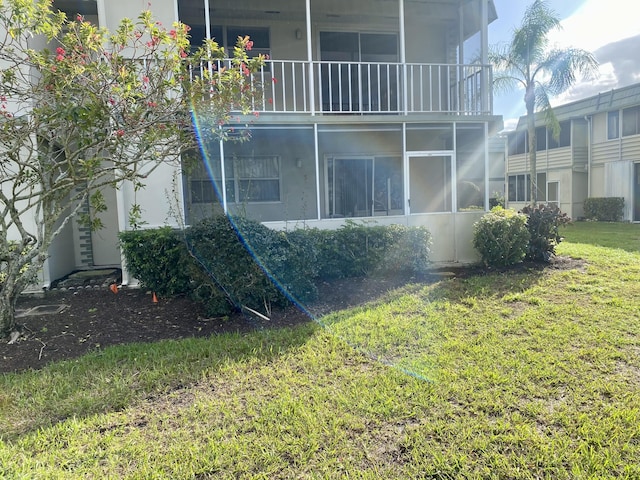 rear view of house featuring a yard and a balcony