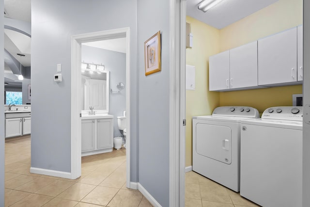 laundry area featuring cabinets, sink, light tile patterned floors, and washing machine and clothes dryer